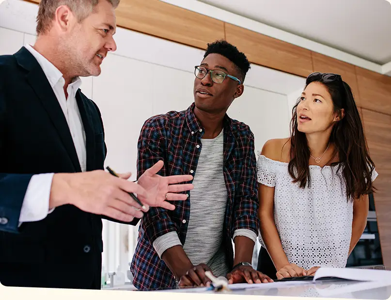 Real estate agent making conversation with a young couple while standing near the kitchen counter.
