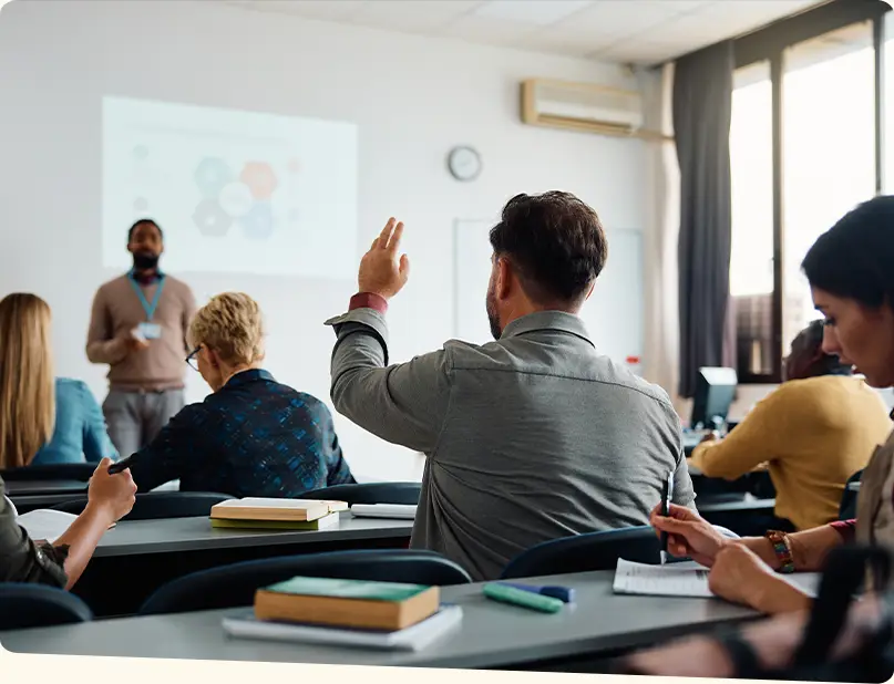 Classroom setting with a student holding his hand up to ask a question