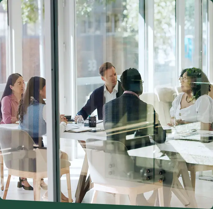 A group of 5 individuals having a discussion in a meeting room