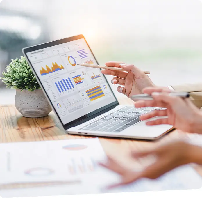 Two individuals looking at graphs on a laptop